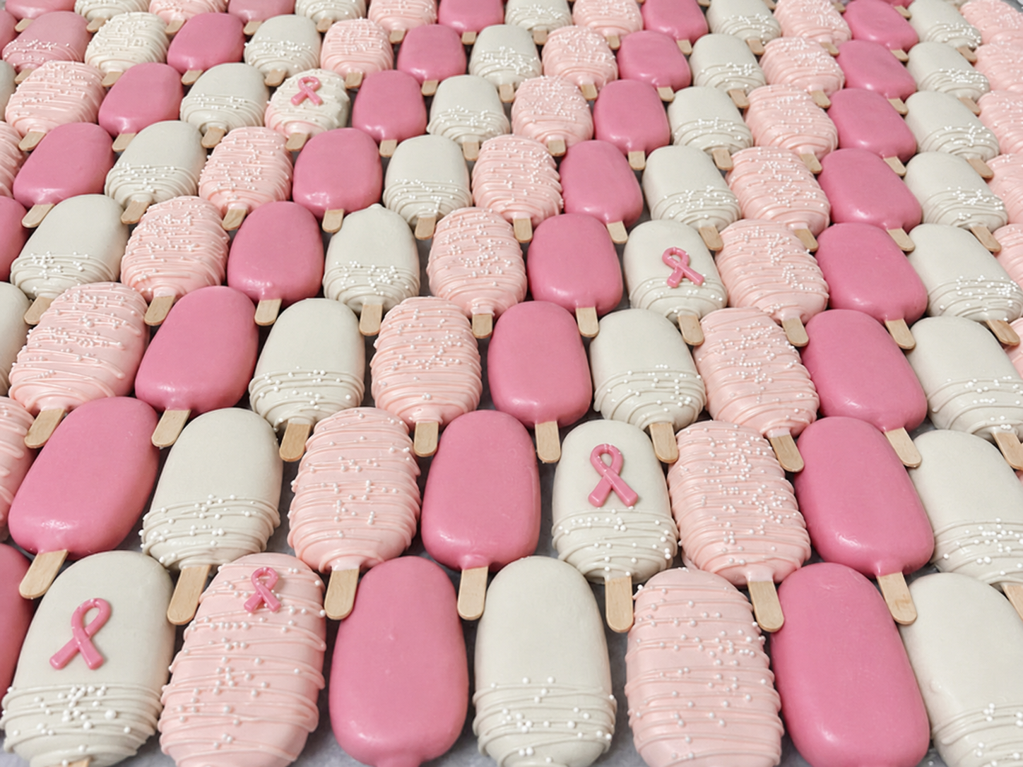 Large pink and white cakesicle fundraiser order with pink ribbons
