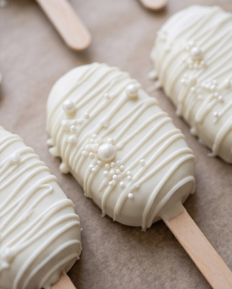 Elegant white cakesicles with pearl sprinkles